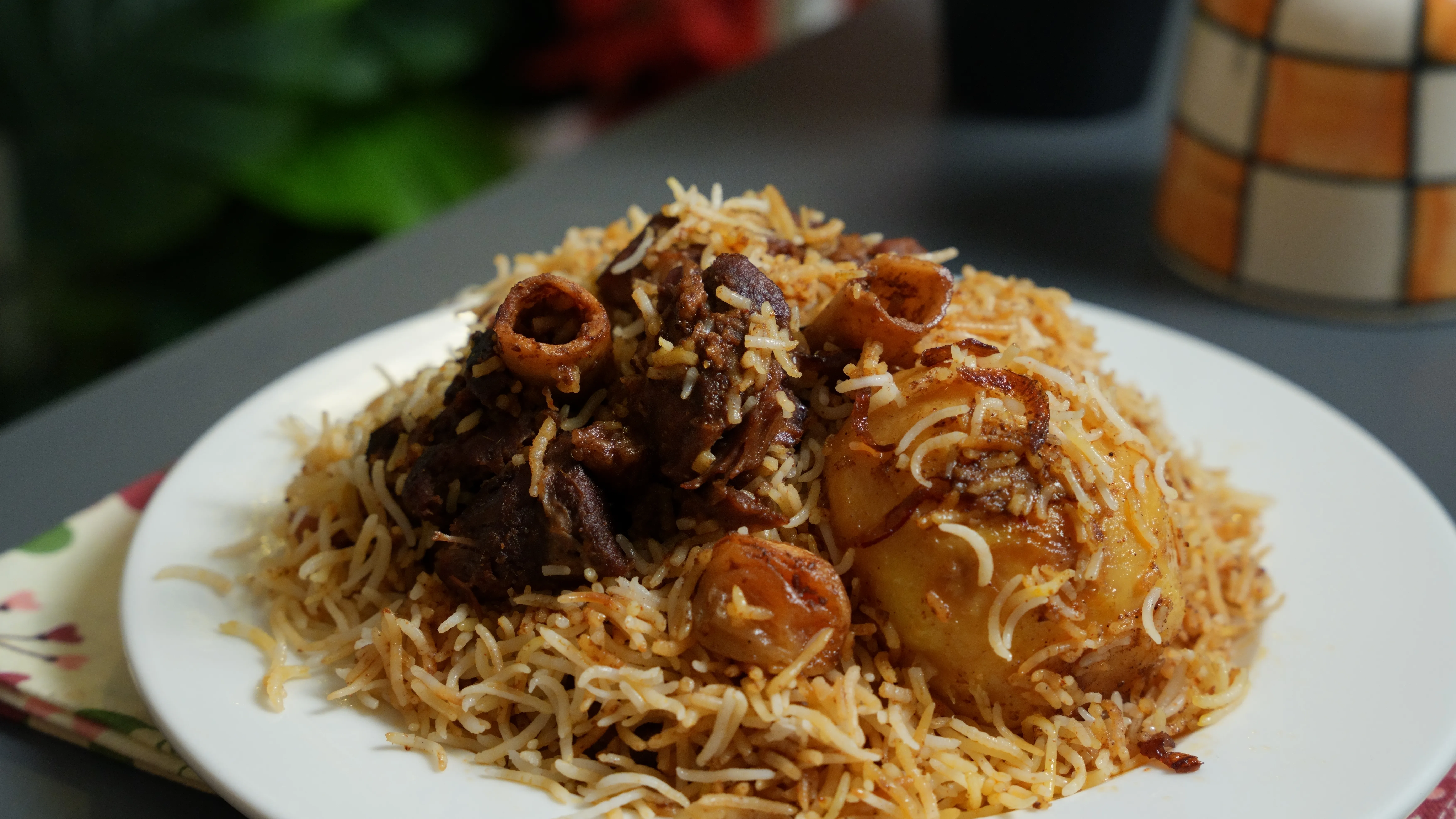 Kolkata Mutton Biryani served with long-grain basmati rice, tender mutton and a golden potato beside the biryani handi.